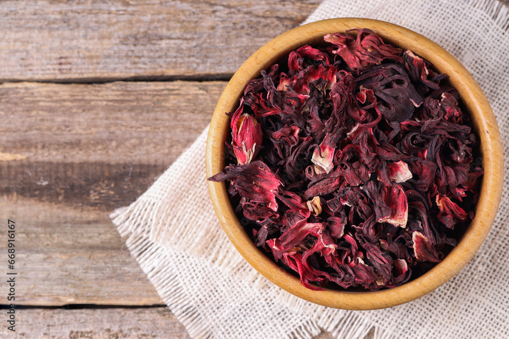 Dry hibiscus tea in bowl on wooden table, top view. Space for text Dry hibiscus tea in bowl on wooden table, top view. Space for text