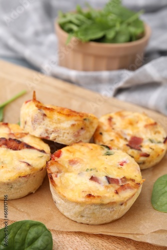 Delicious egg muffins with cheese and bacon on wooden board, closeup. Space for text