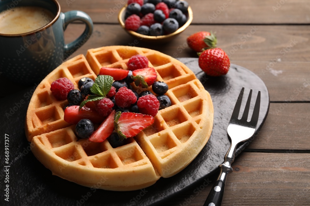 Tasty Belgian waffle with fresh berries served on wooden table, closeup