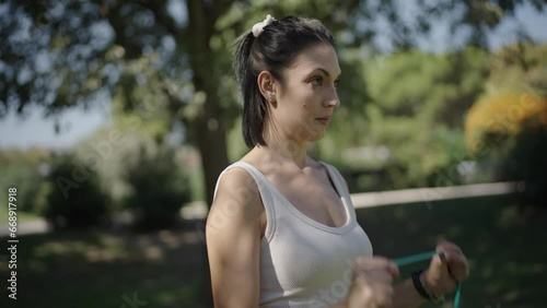 young Spanish woman exercising her body with elastic bands in a park in her city