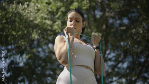 young Spanish woman exercising her body with elastic bands in a park in her city