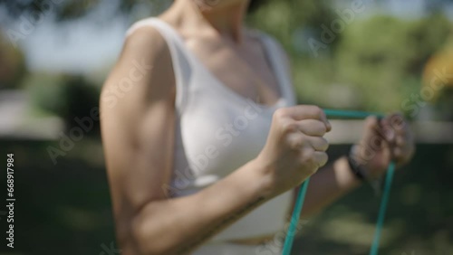 young Spanish woman exercising her body with elastic bands in a park in her city