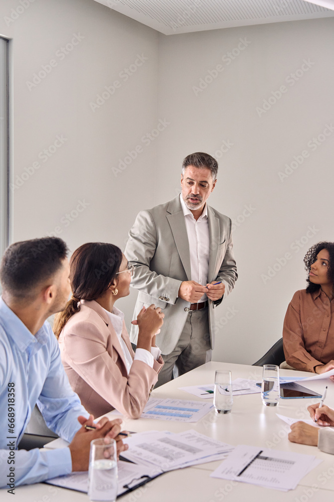 Busy senior company professional executive leader ceo manager leading business conference meeting managing consulting diverse corporate team workers at table in office board room. Vertical - obrazy, fototapety, plakaty 