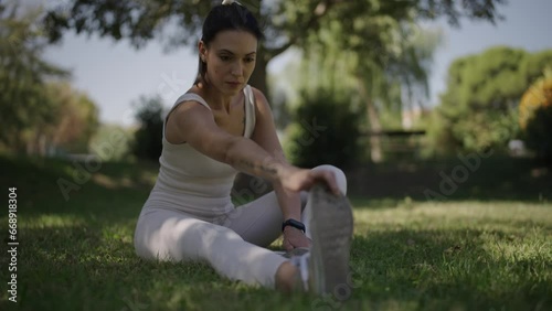 young woman stretching her body in a park on a sunny day