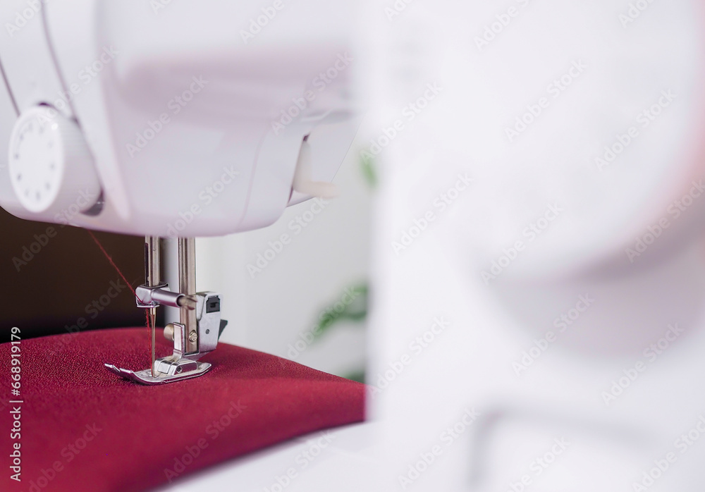 Close up of sewing machine working with red fabric,  stitch new clothing.