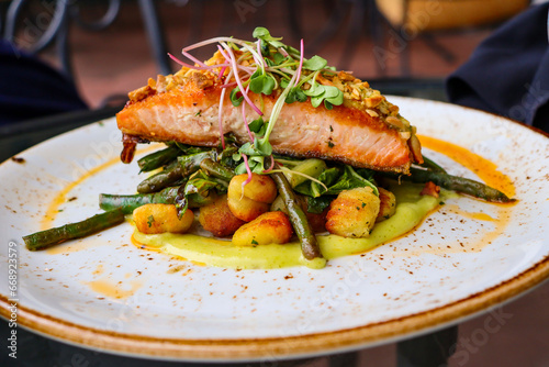fine dining grilled salmon steak on gnocchi and vegetables