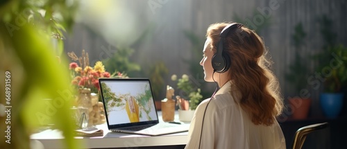 back view of young woman in headphones using laptop and listening to music at home