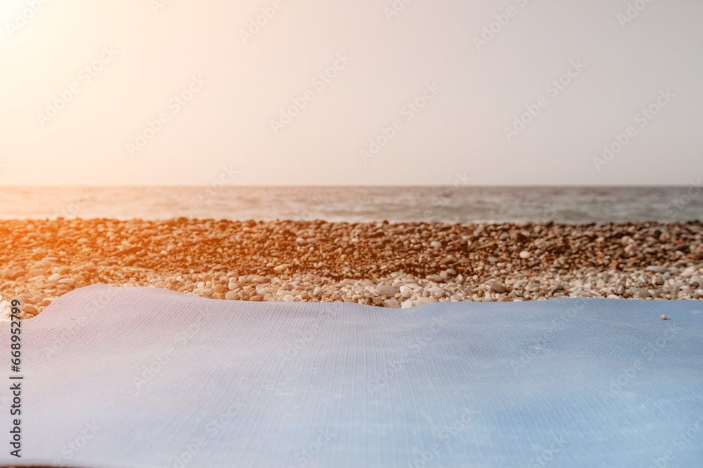 Blue yoga mat is on a sandy pebble beach by the sea. Nobody. Women's yoga fitness routine. Healthy lifestyle, harmony Blue yoga mat is on a sandy pebble beach by the sea. Nobody. Women's yoga fitness routine. Healthy lifestyle, harmony