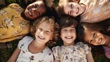 Group of diverse cheerful fun happy multiethnic children lying on field outdoor.