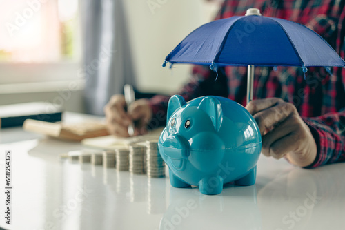 Property insurance guidelines with an umbrella on a piggy bank and a pile of coins on a table photo