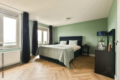 a bedroom with green walls and wood flooring in the middle of the room  there is a large bed on the right side