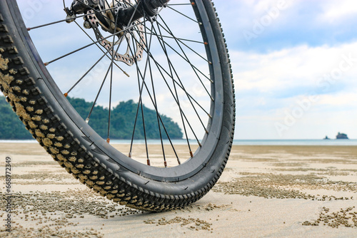 Low angle of a bicycle wheel on the beach, on the sea sand at low tide. The concept of cycling in unusual places. photo