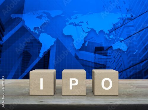 IPO letter on wood block cubes on wooden table over world map, modern office city tower and skyscraper, Initial public offering concept, Elements of this image furnished by NASA