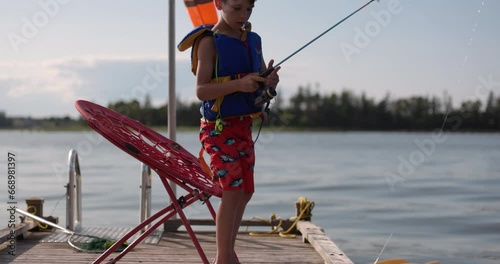 Boy untangles fishing rod on cottage dock - summer fun