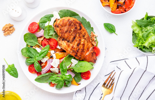 Healthy salad with grilled paprika and chicken, feta cheese, cherry tomatoes, walnut, red onion and lettuce, white table background, top view