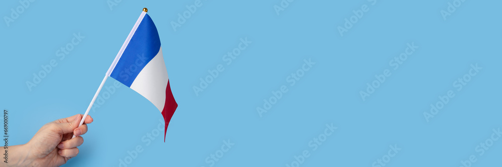 french flag in hand on a blue background, copy space, independence national day of france, country freedom, patriotism