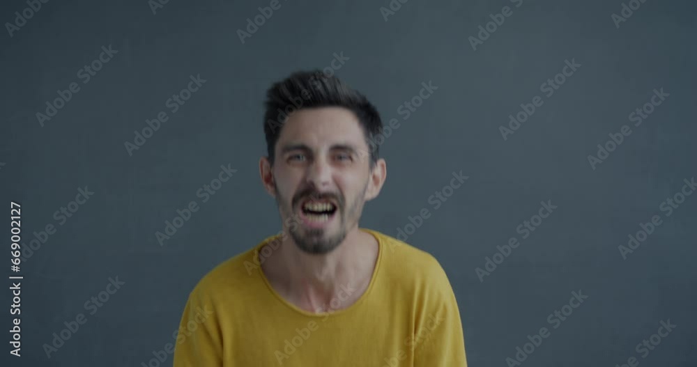 Portrait of angry and desperate man screaming No waving fists and looking at camera on gray background. Negative emotion and people concept. Portrait of angry and desperate man screaming No waving fists and looking at camera on gray background. Negative emotion and people concept.
