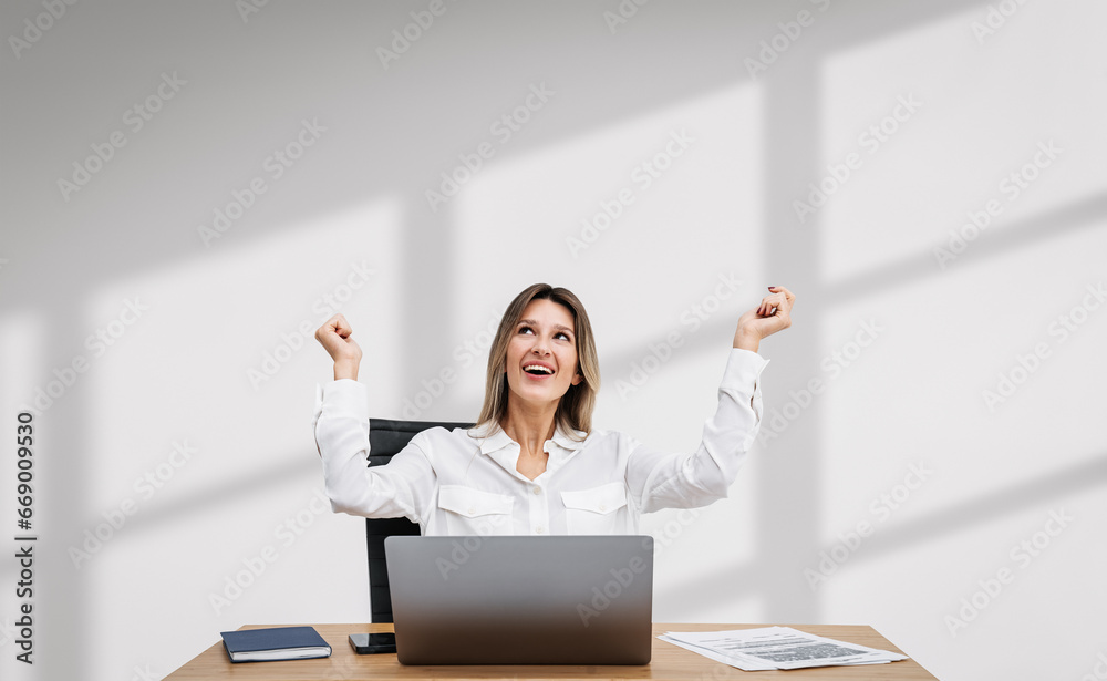Cheerful young woman celebrating at office desk Cheerful young woman celebrating at office desk