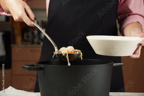 Woman adding at chicken soup, chicken broth, in a bowl. Healthy food concept