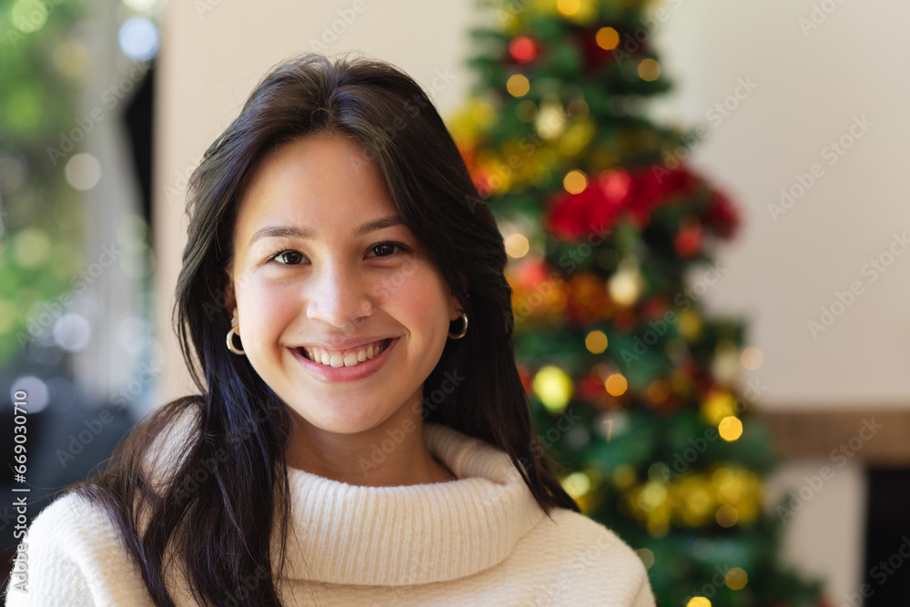 Portrait of happy diverse woman with decorated christmas tree at home, copy space Portrait of happy diverse woman with decorated christmas tree at home, copy space