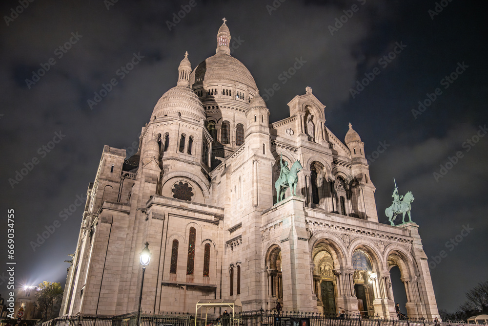 The Basilica of Sacre Coeur de Montmartre illuminated in the evening. Roman Catholic church and minor basilica in Paris dedicated to the Sacred Heart of Jesus. France