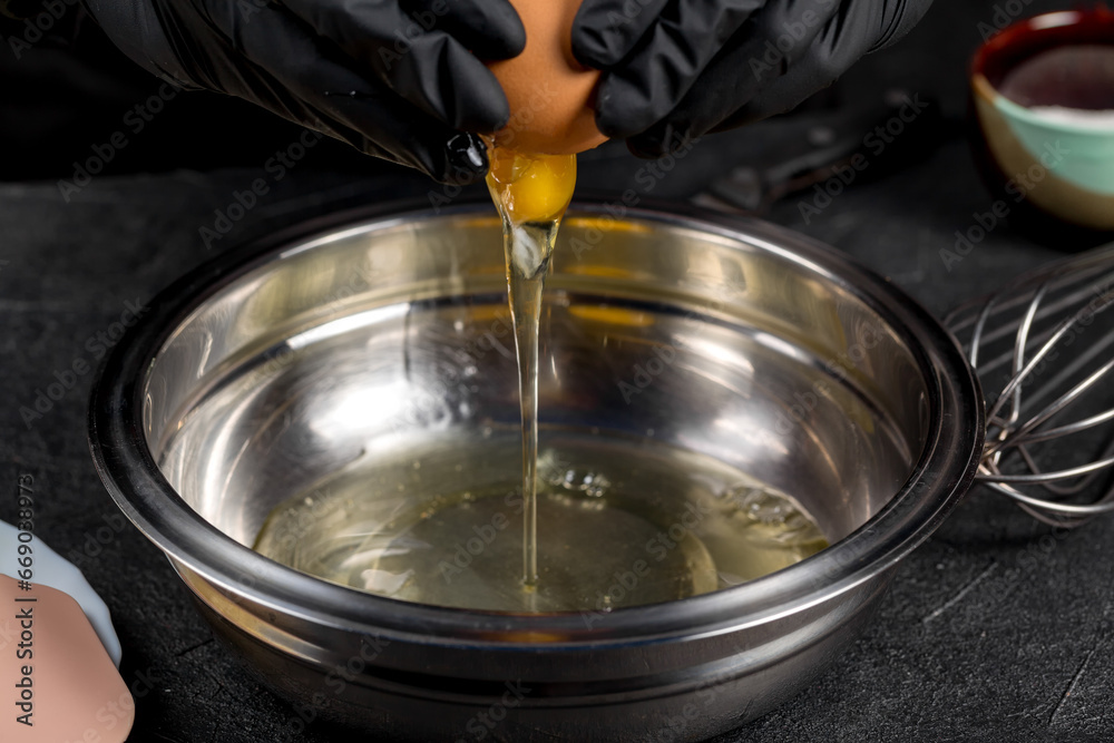 Cracking raw eggs into a bowl for making a cake Cracking raw eggs into a bowl for making a cake