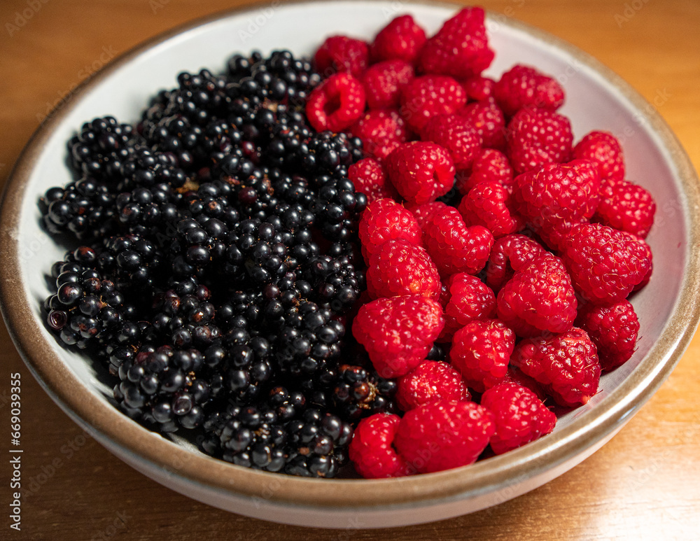 Summer berries, raspberries, blackberries. Dessert on a white plate. Vitamins, healthy nutrition. Fresh raspberries and blackberries on plate lined with symbol of yin and yang Summer berries, raspberries, blackberries. Dessert on a white plate. Vitamins, healthy nutrition. Fresh raspberries and blackberries on plate lined with symbol of yin and yang