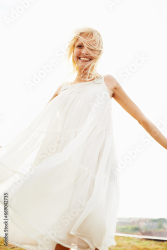 Portrait, happy woman and dress in wind outdoor on vacation, holiday or travel in summer. Freedom, smile and confident blonde person standing in nature, garden or countryside with sky in Amsterdam