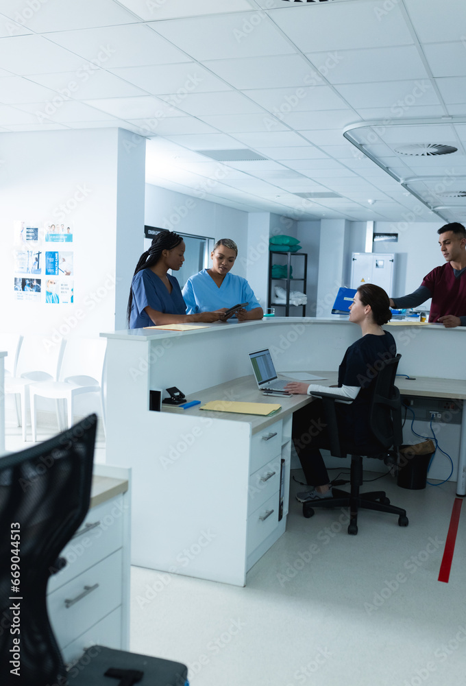 Diverse female doctors discussing work, using tablet at reception desk at hospital Diverse female doctors discussing work, using tablet at reception desk at hospital