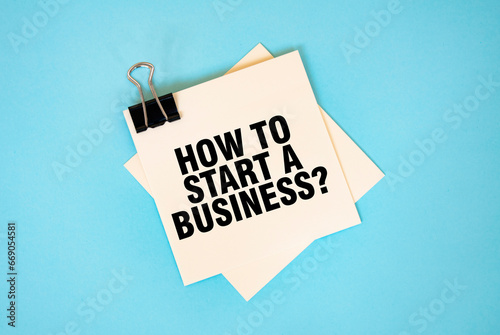 Text HOW TO START A BUSINESS on sticky notes with copy space and paper clip isolated on red background. Finance and economics concept.