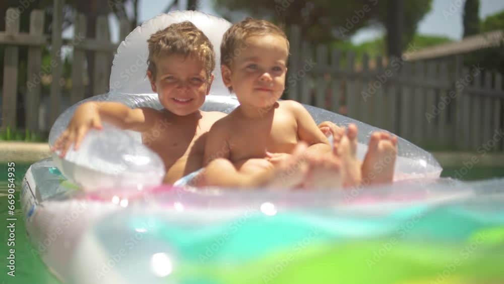 Two little brothers playing together in the pool on a sunny day of summer, in a sweet and happy way Two little brothers playing together in the pool on a sunny day of summer, in a sweet and happy way