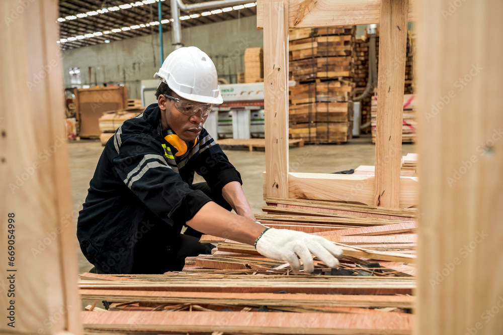 Black carpenter working with wood in pile wood warehouse Black carpenter working with wood in pile wood warehouse