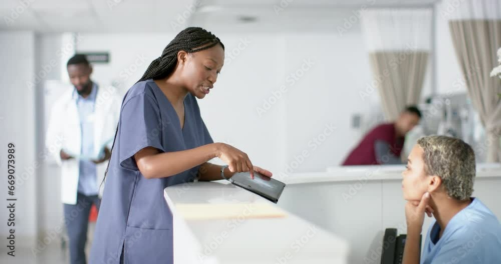 Diverse female doctors discussing work, using tablet at reception desk at hospital, slow motion Diverse female doctors discussing work, using tablet at reception desk at hospital, slow motion