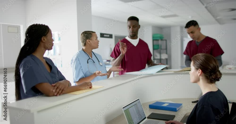 Diverse male and female doctors discussing work at reception desk at hospital, slow motion Diverse male and female doctors discussing work at reception desk at hospital, slow motion