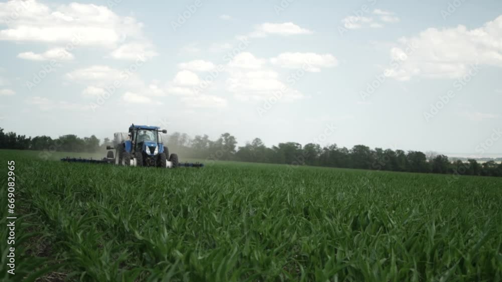 Tractor on the field of green corn fertilizing the crop Tractor on the field of green corn fertilizing the crop
