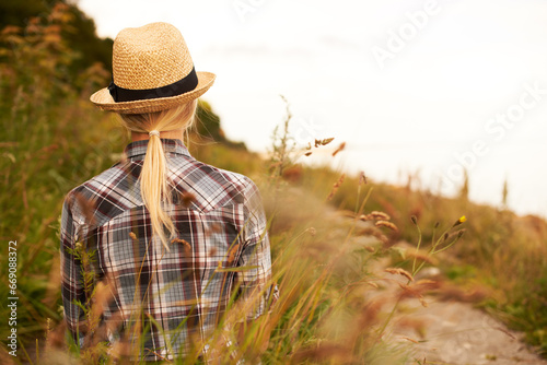 Woman, walk and relax in field or nature, peace and back in outdoors, meadow and flowers or plants. Female person, hike and trekking for fitness, exercise and health or wellness, grass and vacation © Jeff Bergen/peopleimages.com