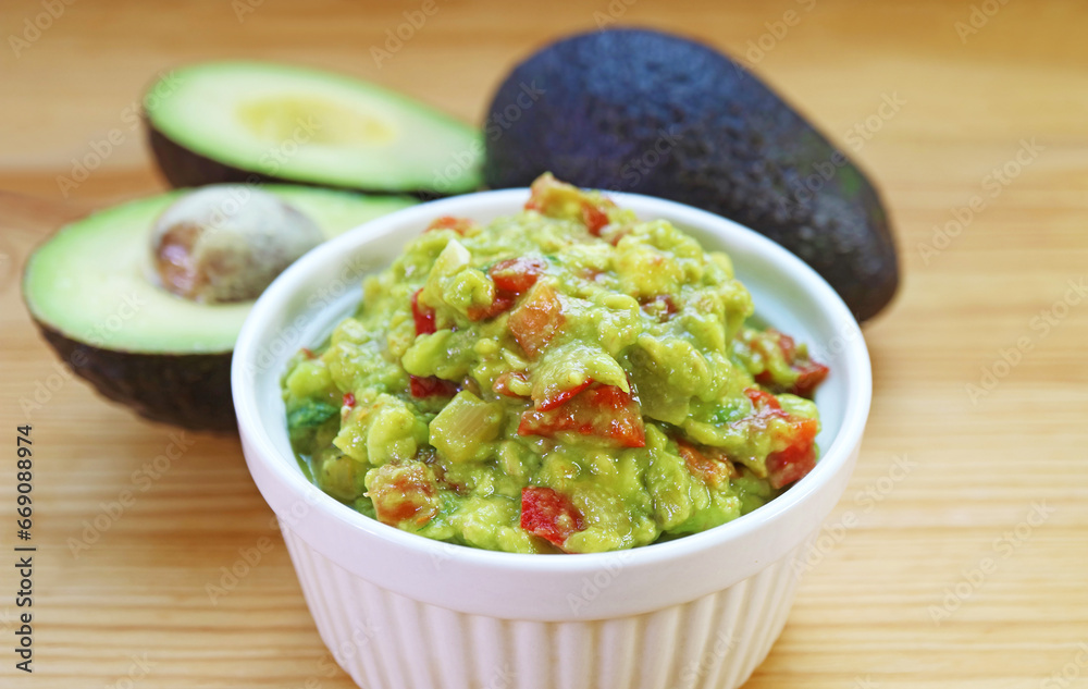Closeup of Homemade Guacamole with Blurry Fresh Avocadoes in the Backdrop Closeup of Homemade Guacamole with Blurry Fresh Avocadoes in the Backdrop