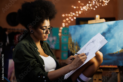 фотографія Young afican american female artist drawing sketches in art workshop