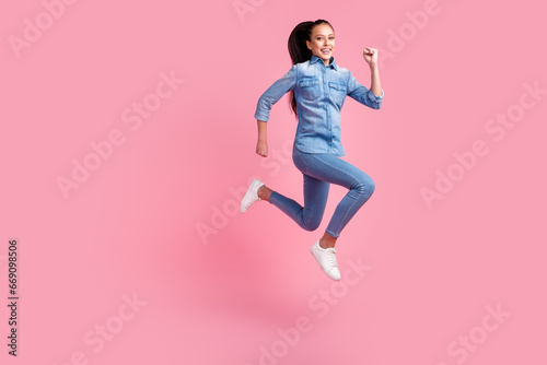 Photo of pretty charming woman dressed denim outfit jumping running fast empty space isolated pink color background