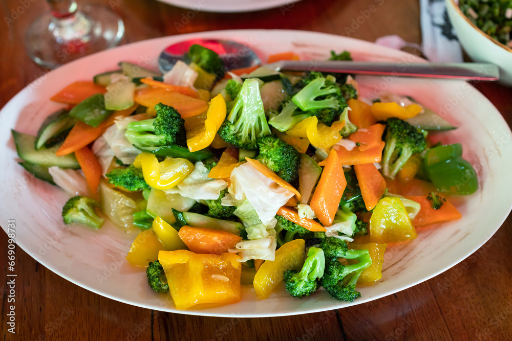 Chinese cuisine - lightly fried fresh vegetables with broccoli on plate on table close up