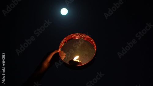 Young Indian woman celebrating Karva Chauth at night. Karva Chauth is a one-day festival celebrated by Hindu women four days after purnima (a full moon) in the month of Kartika. photo
