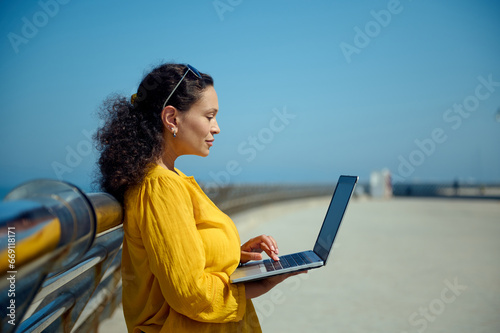 Side portrait of a beautiful middle aged woman using laptop, working remotely outdoors. People. Online business. Career