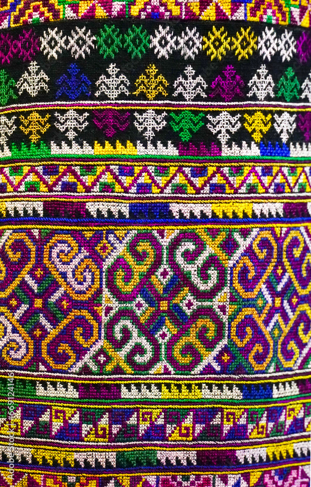 Thai cloth with Khit pattern.Abstract background, texture colorful, space for work, banner, wallpaper, selective focus of Thai traditional handmade with weaving technique is called ikat.Vertical.