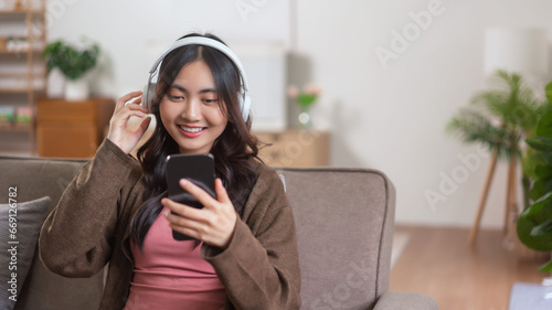Women wearing headphones and watching movie with entertainment on smartphone in lifestyle at home