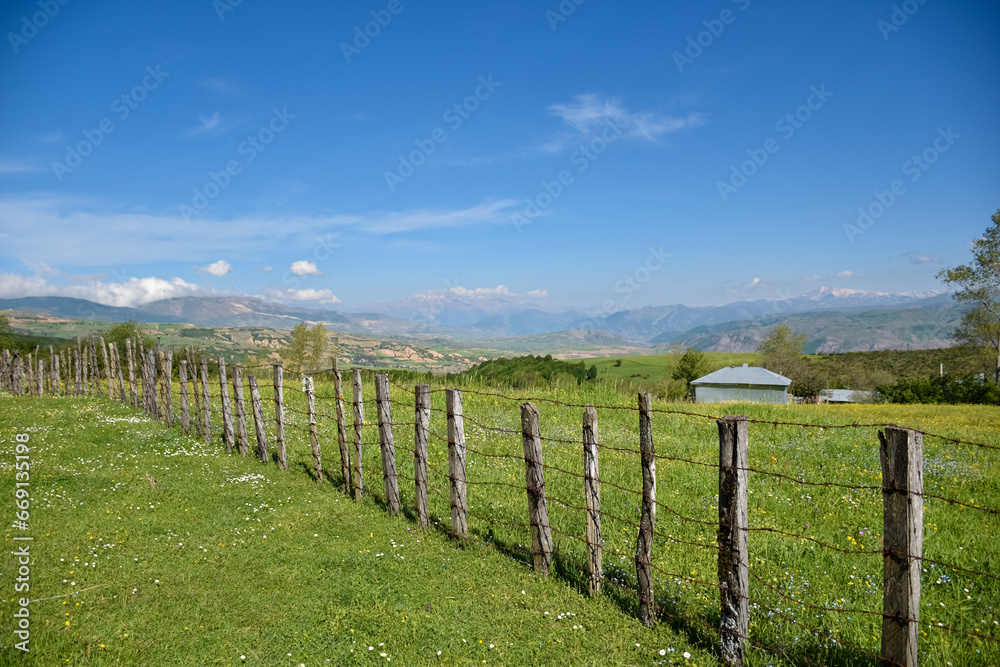The wooden fence of a rural cottage in the heights and the beautiful view of the mountains
