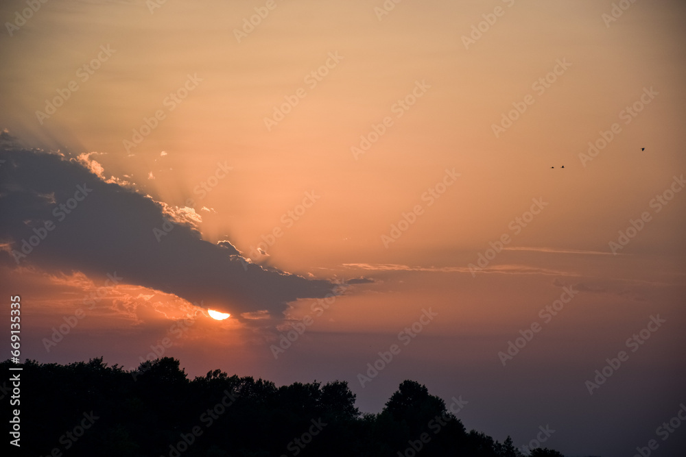 Fototapeta premium Sunset behind the clouds and mountain and forest view