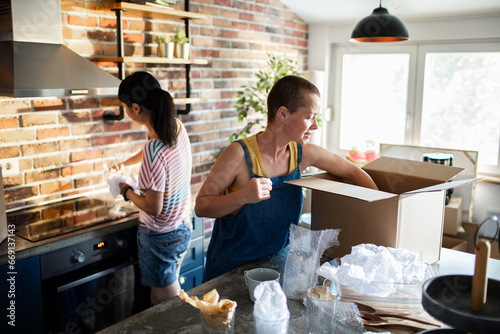 A lesbian couple unpacks kitchen items in their new home photo