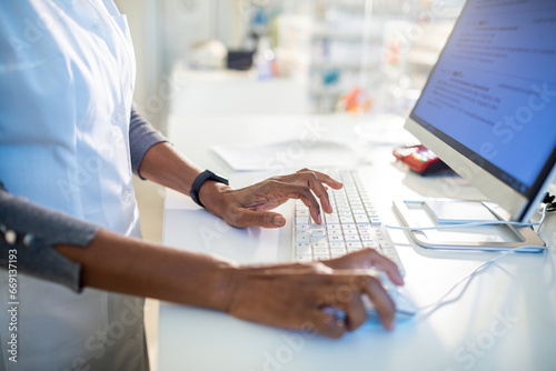 Pharmacist typing on a computer in the drugstore photo