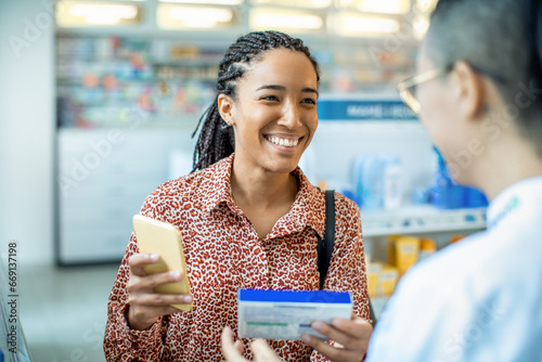 Young African American woman consulting a pharmacist about medication at the pharmacy