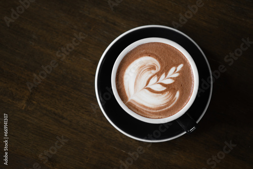 Top view of hot latte coffee or chocolate  with latte art in the cup on the wooden table. Cafe drink and food menu concept. Copy space for text.